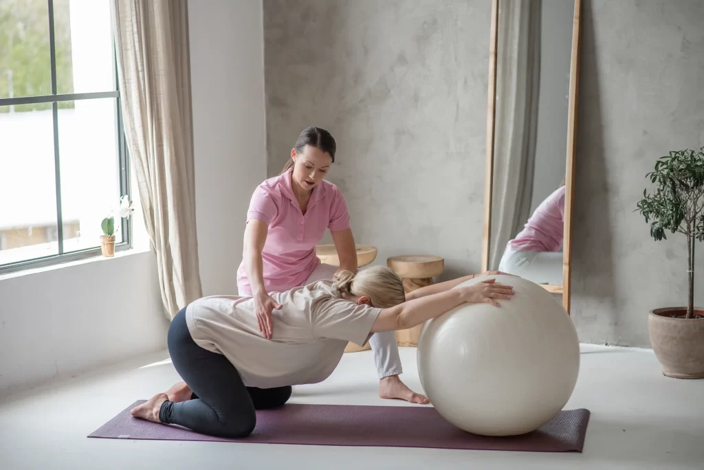 Iván Edina gyógytornász gerinctornát vezet manuálterápiás gyakorlattal fitball labdán, Dunaharaszti Fiziopro